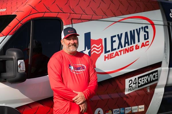 A Lexany's Heating & AC technician beside the company service van in Forney, TX