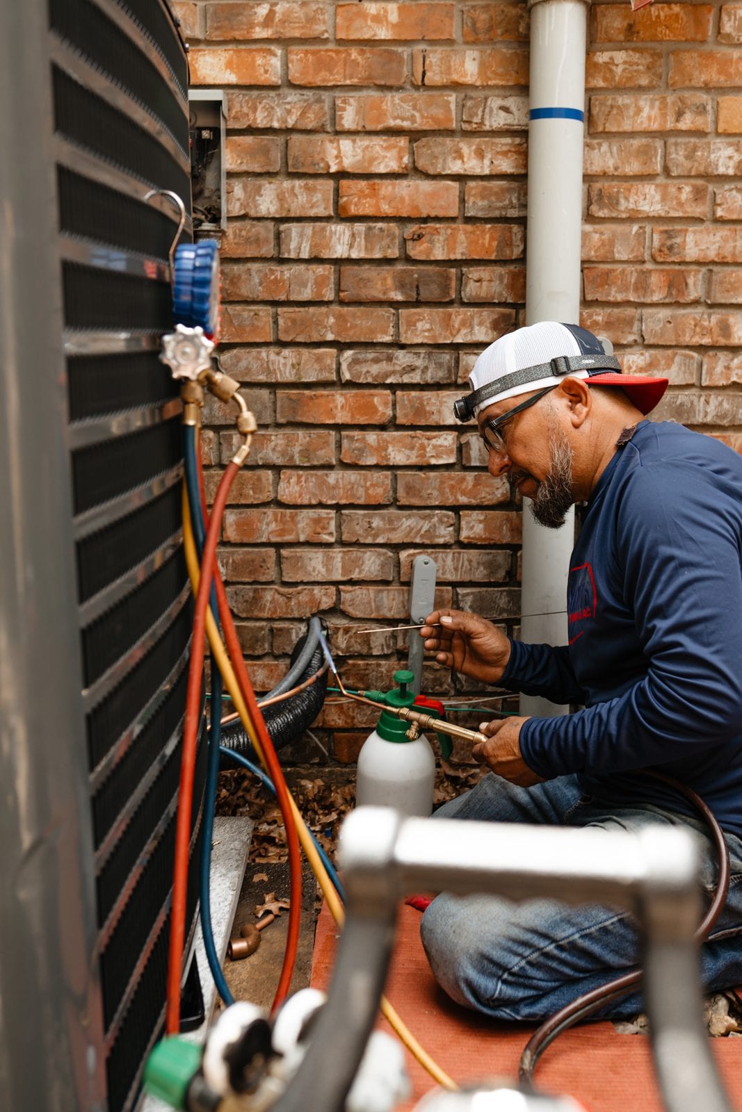 A Lexany's Heating & AC technician checking system gauges at a home